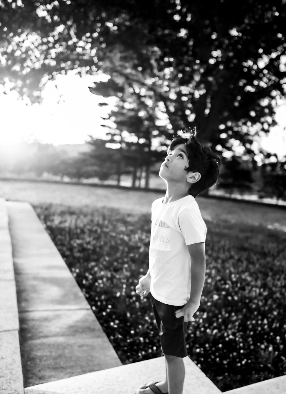 grayscale photo of girl in white shirt and black pants standing on pathway