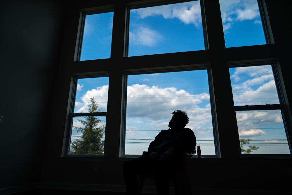 man sitting on chair near window