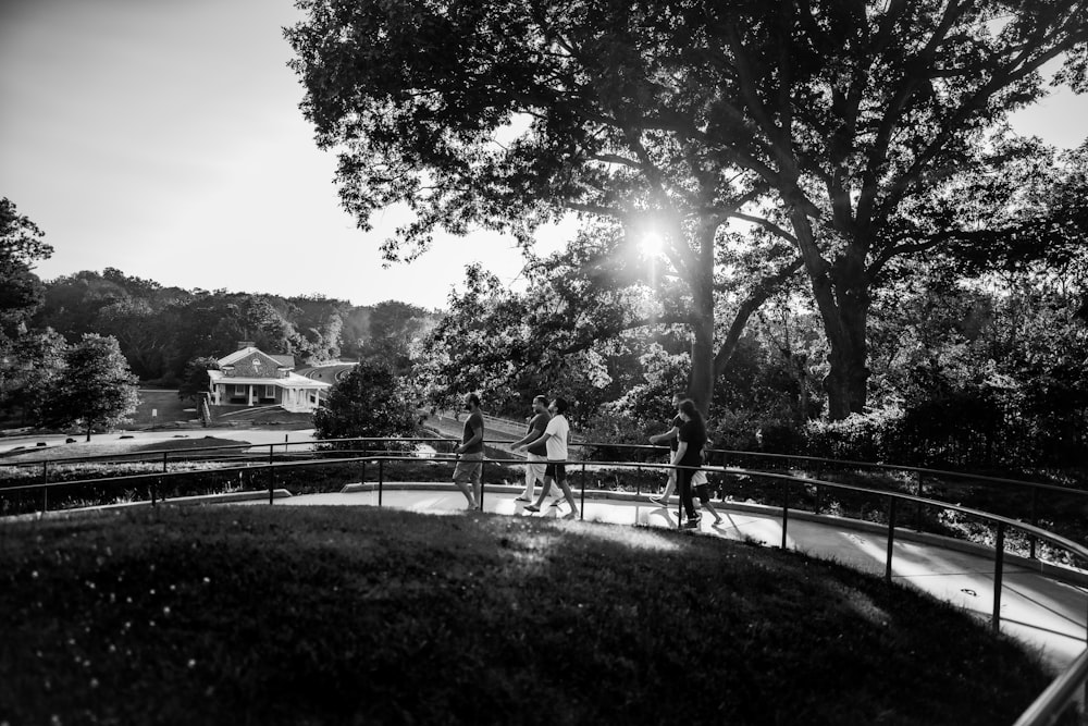 grayscale photo of people sitting on bench near trees