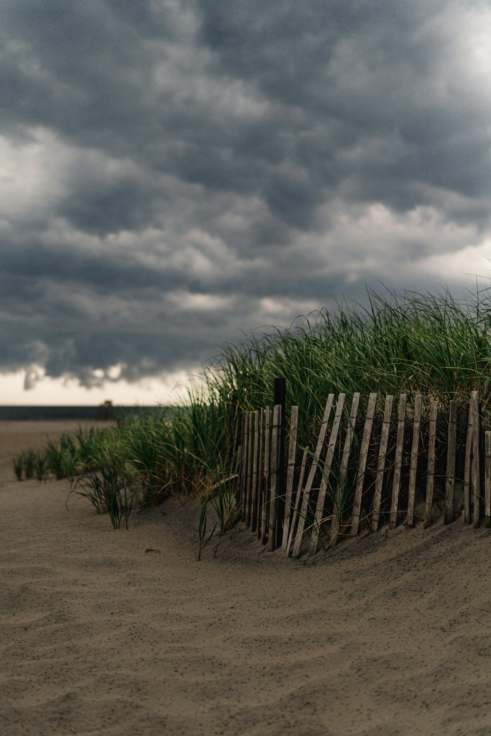 clôture en bois marron sur sable brun sous des nuages gris