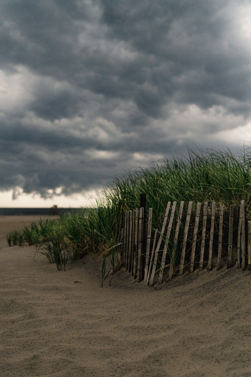 valla de madera marrón sobre arena marrón bajo nubes grises