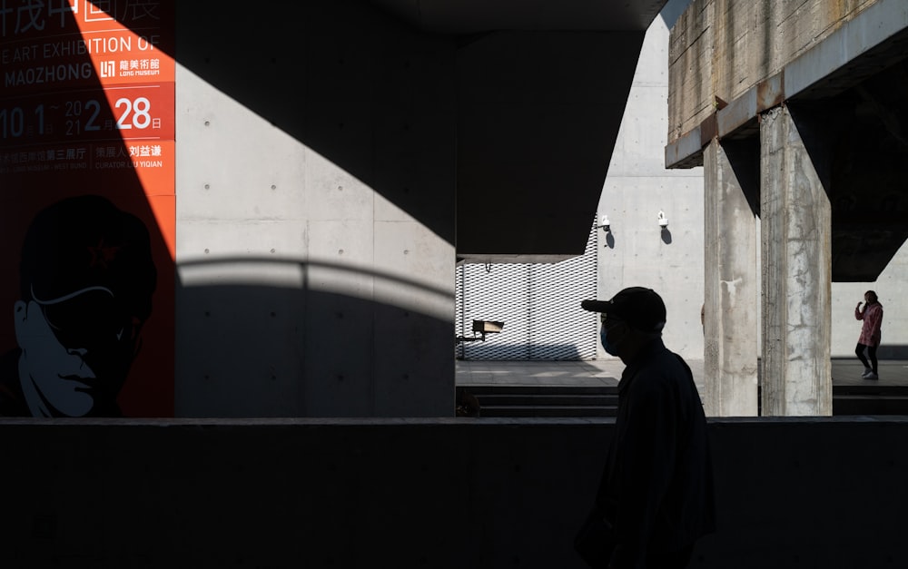 man in black jacket standing near white wall