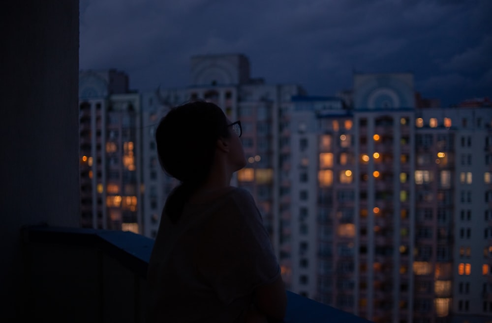 woman in white shirt standing on top of building during night time