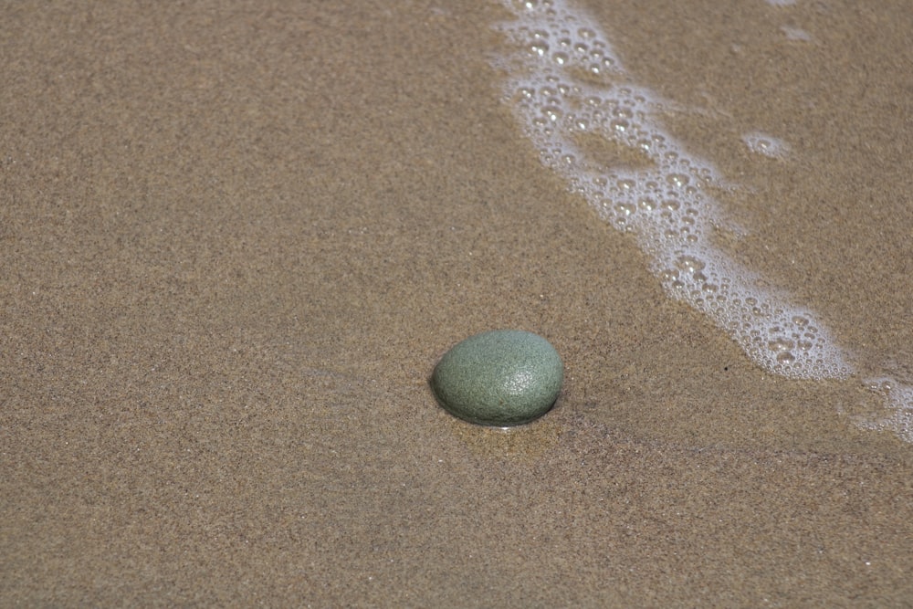 palla rotonda verde su sabbia marrone