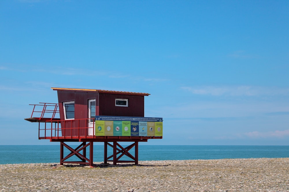 낮 동안 해변 해안에 있는 빨간색과 흰색 목조 인명 구조원 집