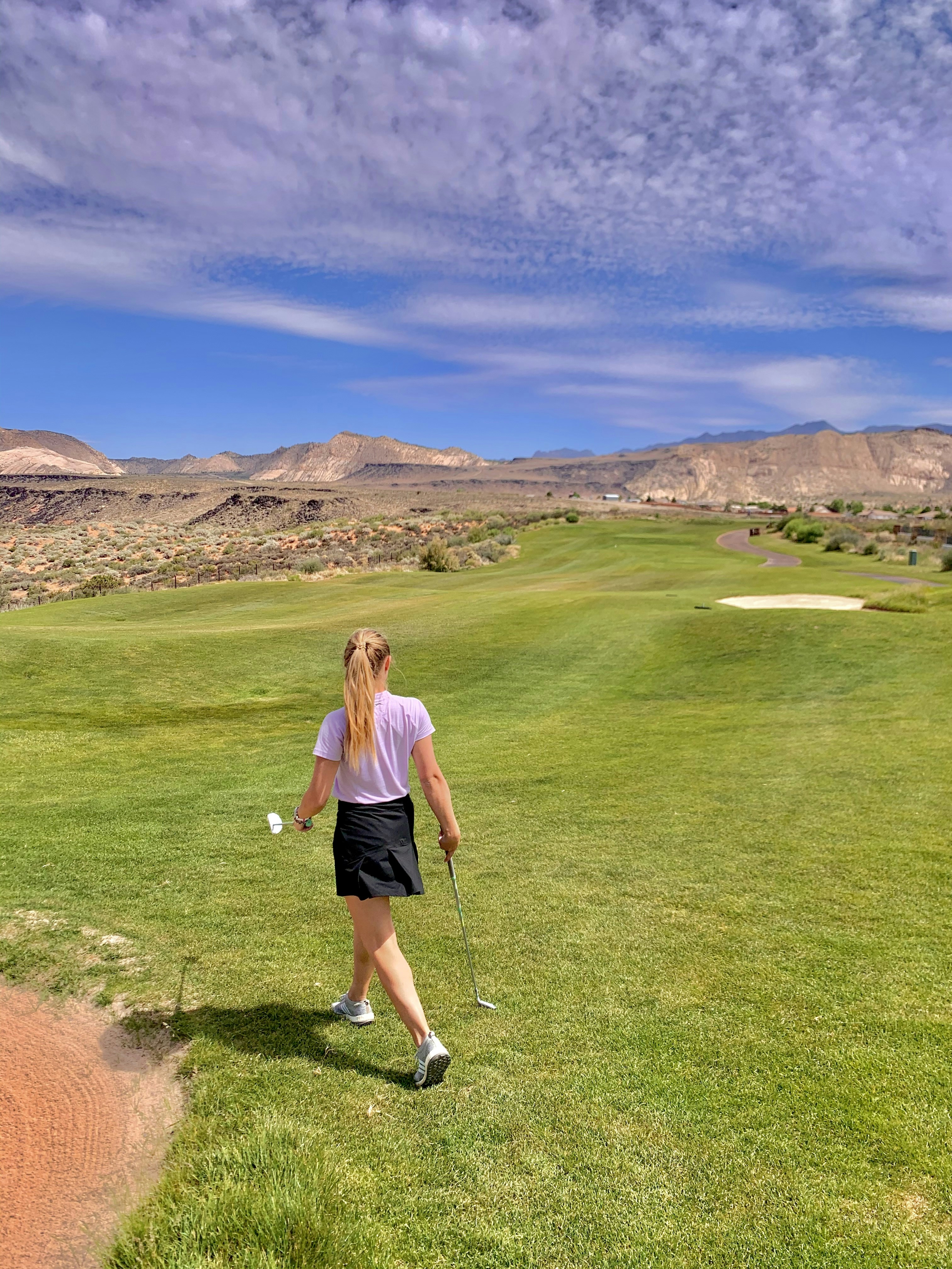 woman in white tank top and black shorts standing on green grass field during daytime