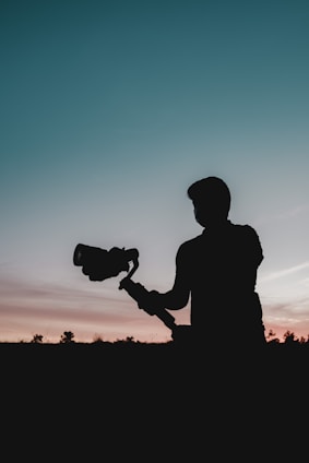 silhouette of man holding camera during sunset