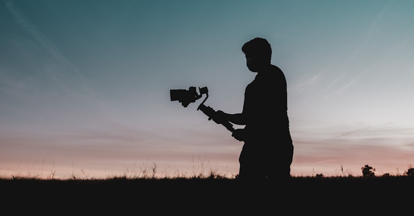 silhouette of man holding camera during sunset