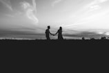silhouette of man and woman kissing on grass field under cloudy sky during daytime