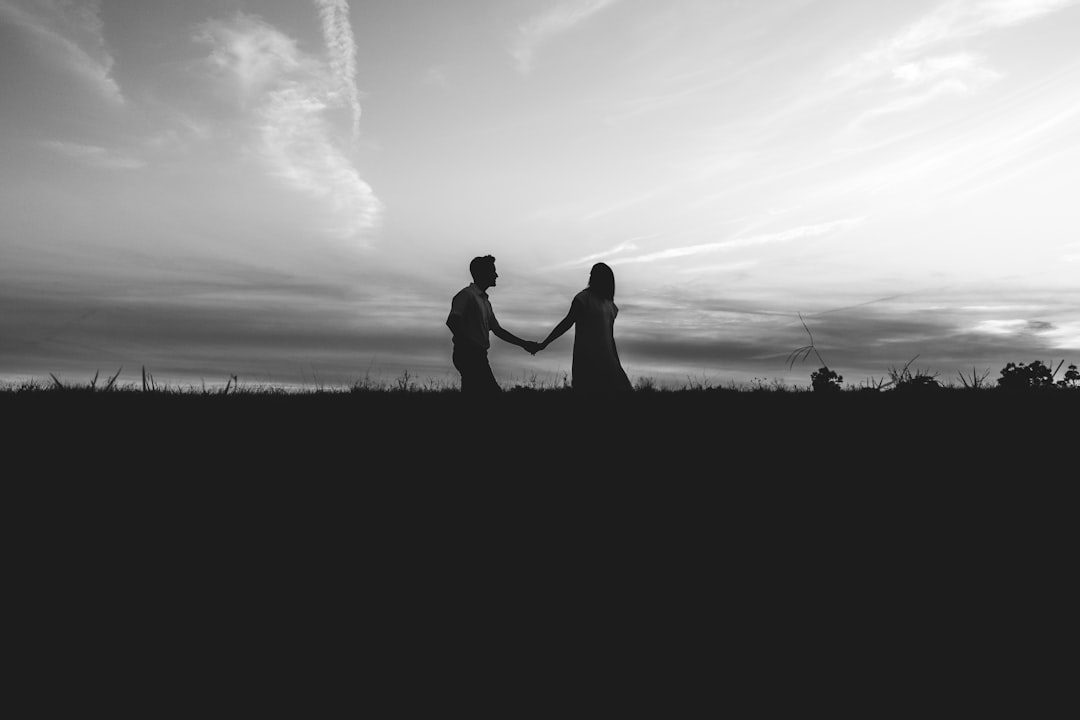 silhouette of man and woman kissing on grass field under cloudy sky during daytime
