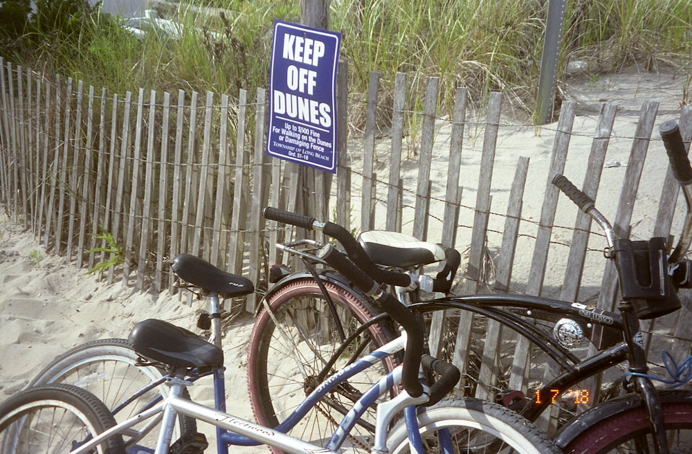 black city bike parked beside white wooden fence