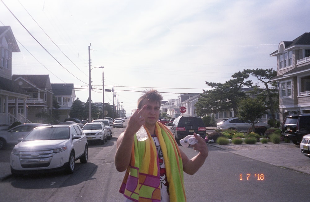 man in green yellow and pink stripe shirt standing on road during daytime