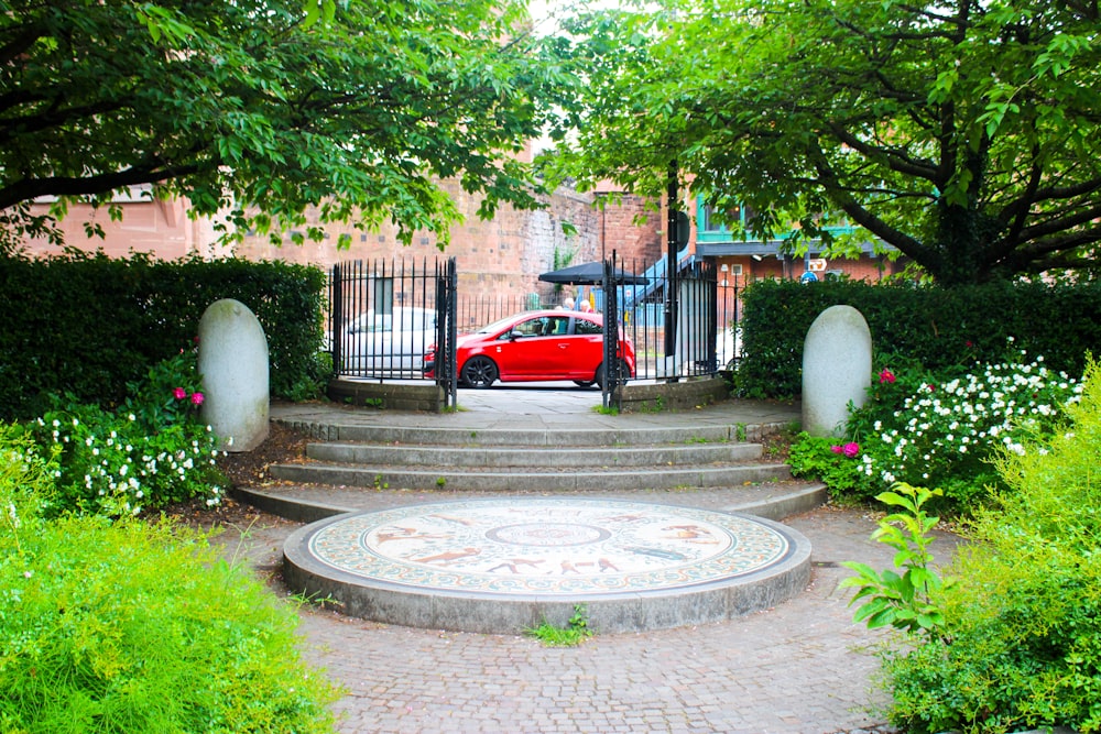 auto rossa parcheggiata vicino al cancello di cemento bianco