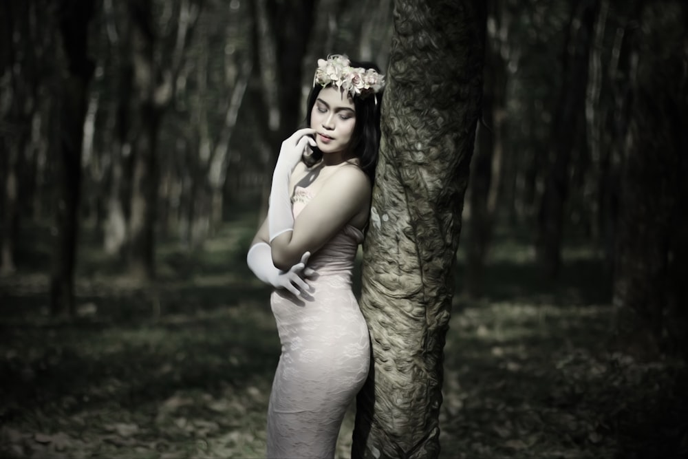 woman in white dress leaning on tree