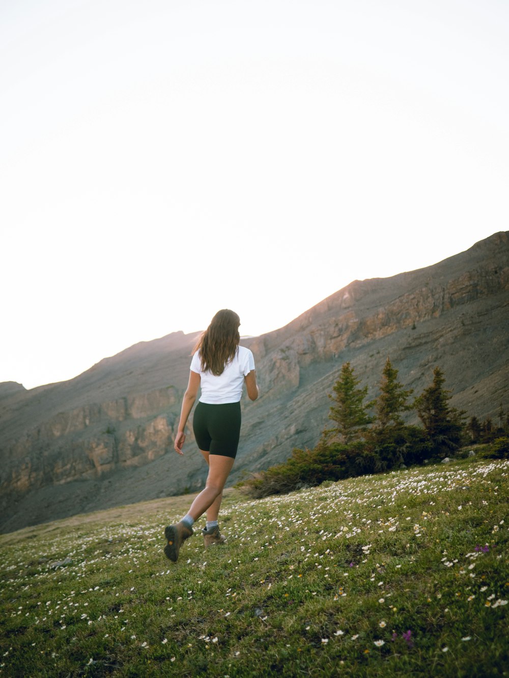 woman in white tank top and black shorts running on green grass field during daytime