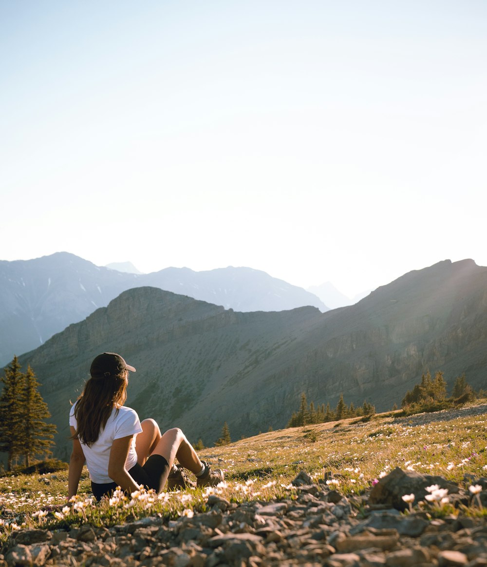 woman in white tank top sitting on brown rock during daytime