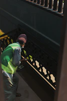 Team member wearing gloves and uniform cleaning a stairwell handrail carefully.