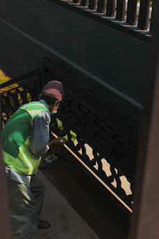 A professional cleaner carefully washing stair railings in a residential building.