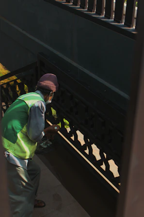 Team member wearing gloves and uniform cleaning a stairwell handrail carefully.