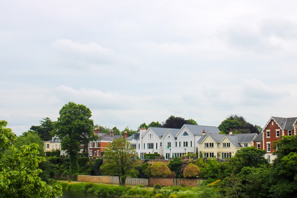 white and brown concrete house near green trees under white sky during daytime