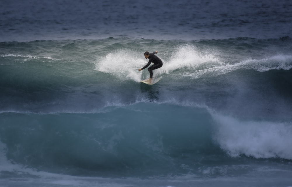 Mann surft tagsüber auf blauen Meereswellen
