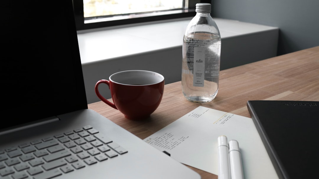 clear plastic bottle beside red ceramic mug