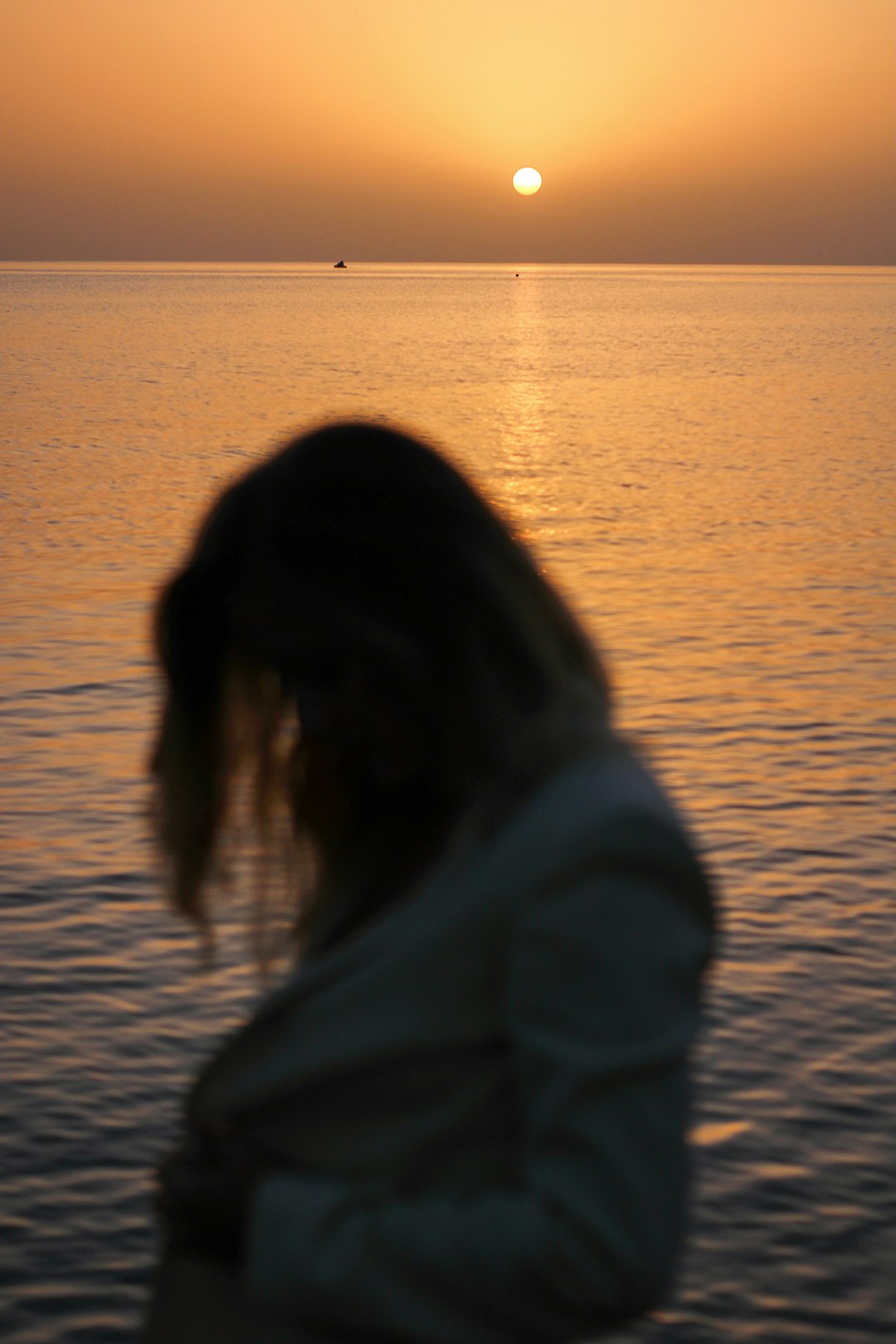 woman in white long sleeve shirt standing on seashore during sunset