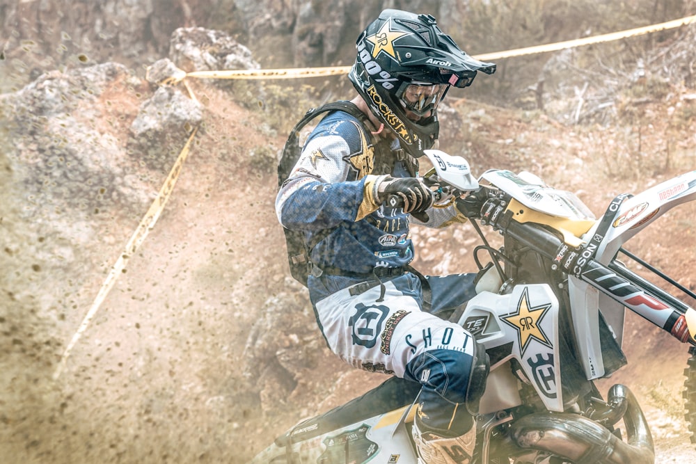 Homme en casque blanc et noir conduisant une moto tout-terrain de motocross