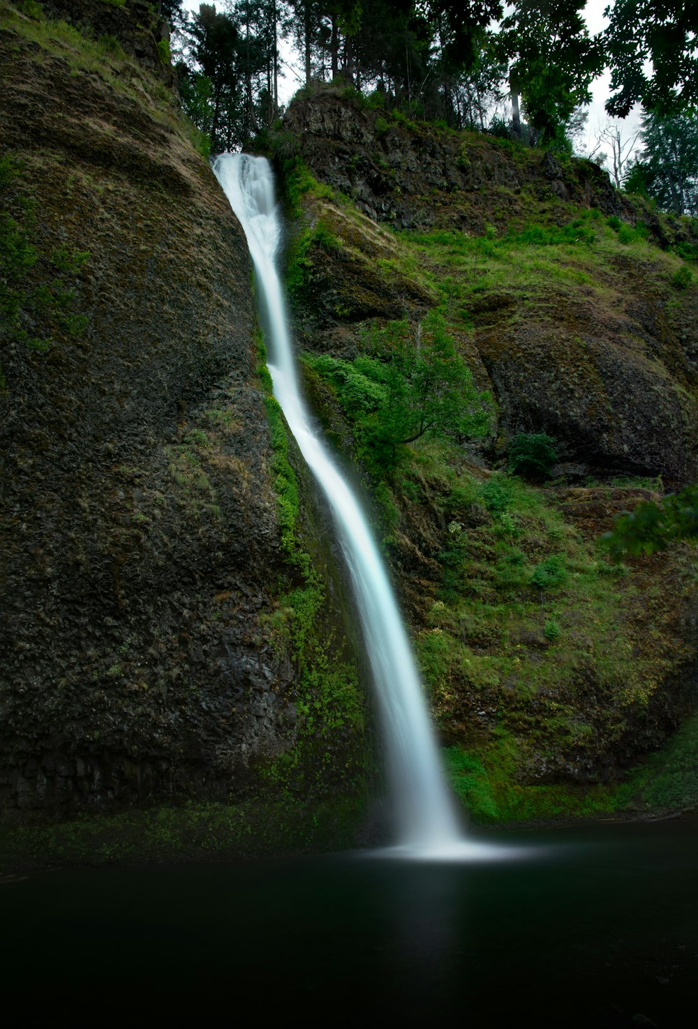 water falls in the middle of green grass field