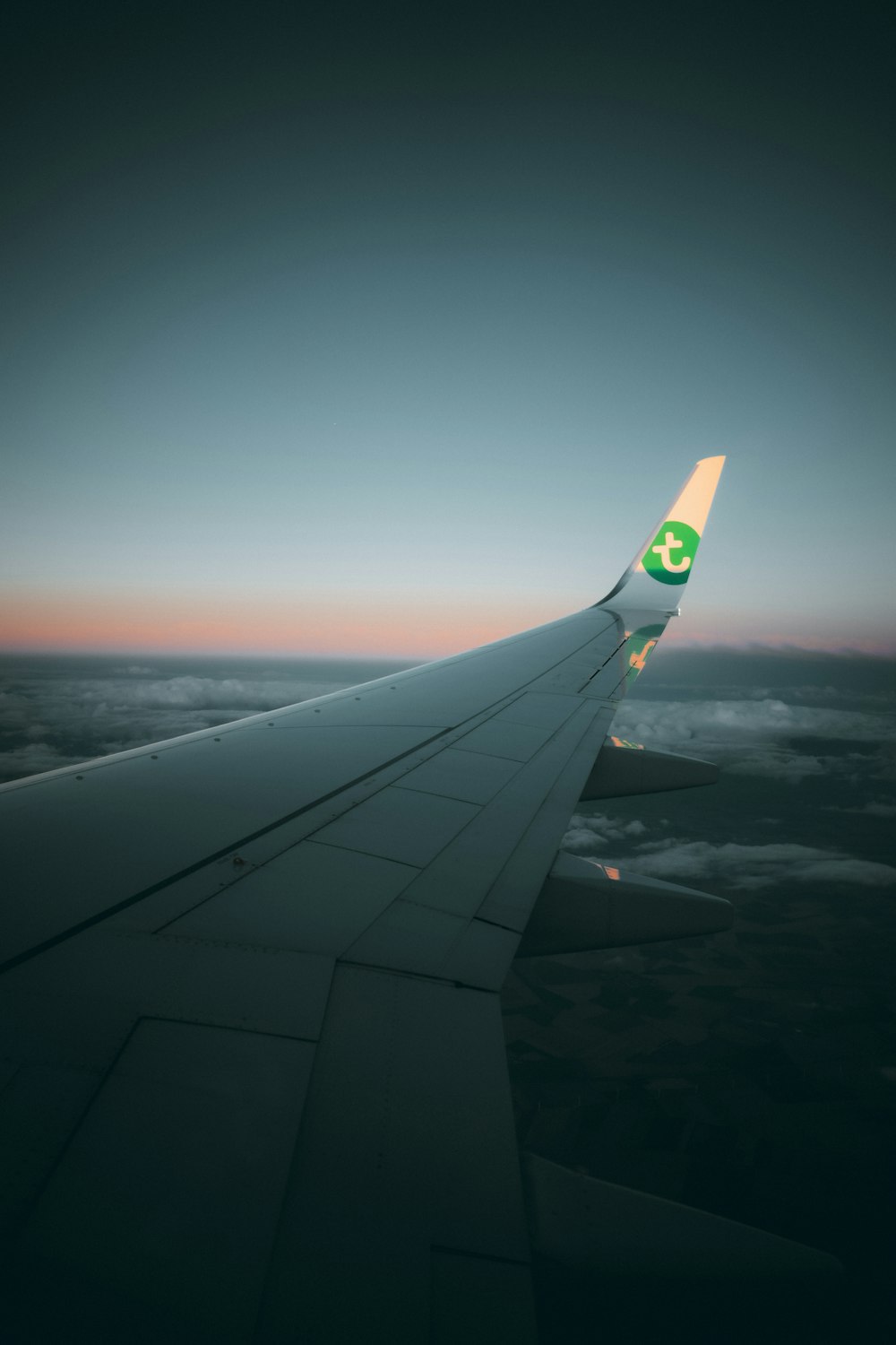 white and blue airplane wing during sunset