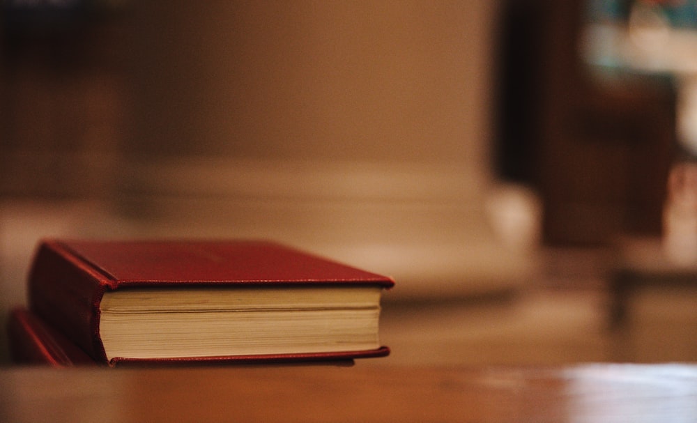 茶色の木製のテーブルに赤いハードカバーの本