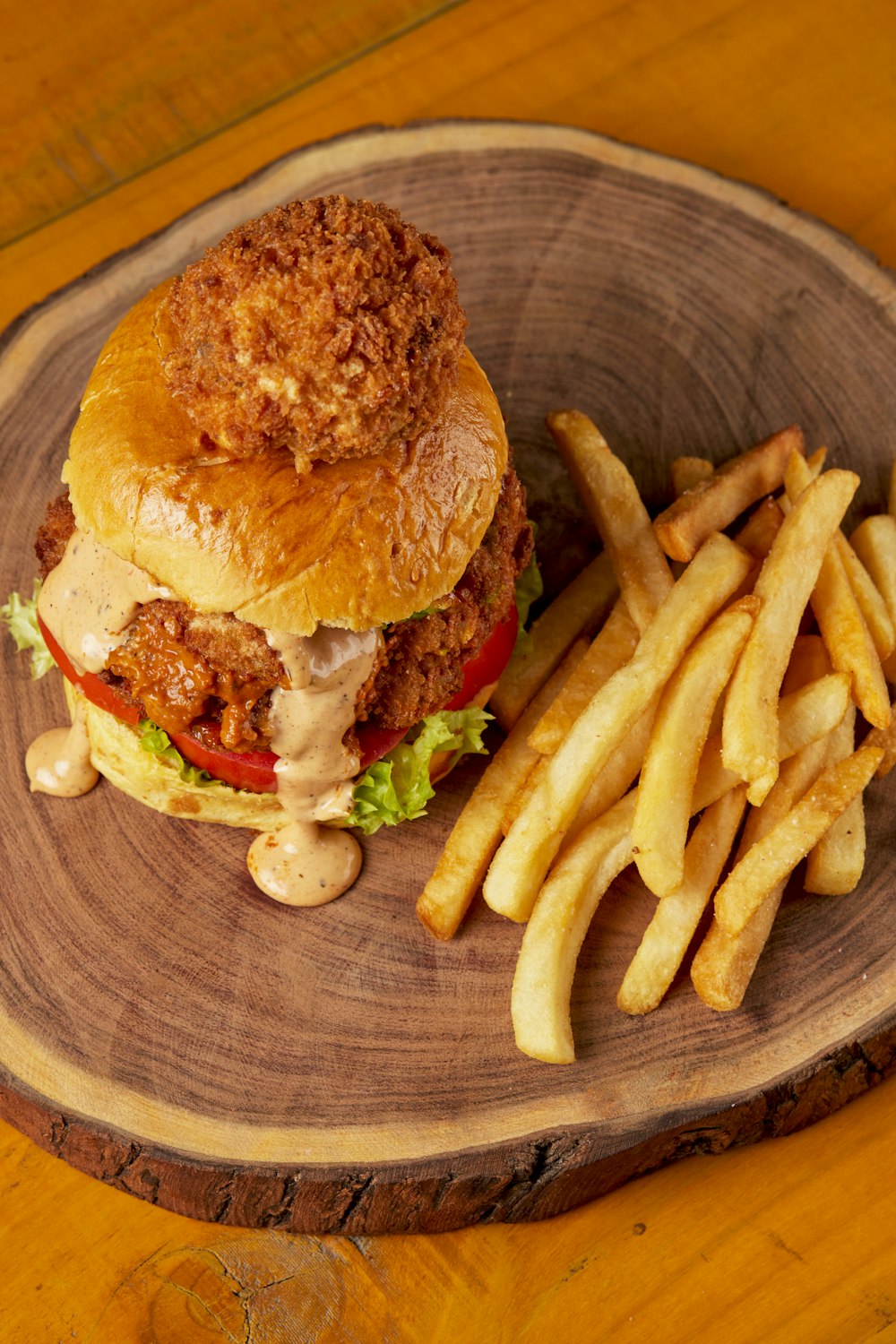 burger and fries on brown wooden round plate