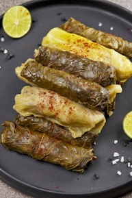 Fresh grape leaves and ingredients laid out on a wooden table ready for cooking.