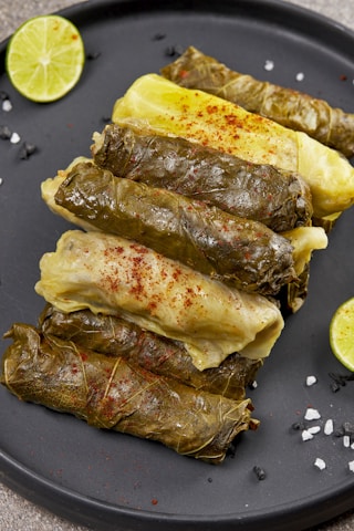Fresh grape leaves and ingredients laid out on a wooden table ready for cooking.