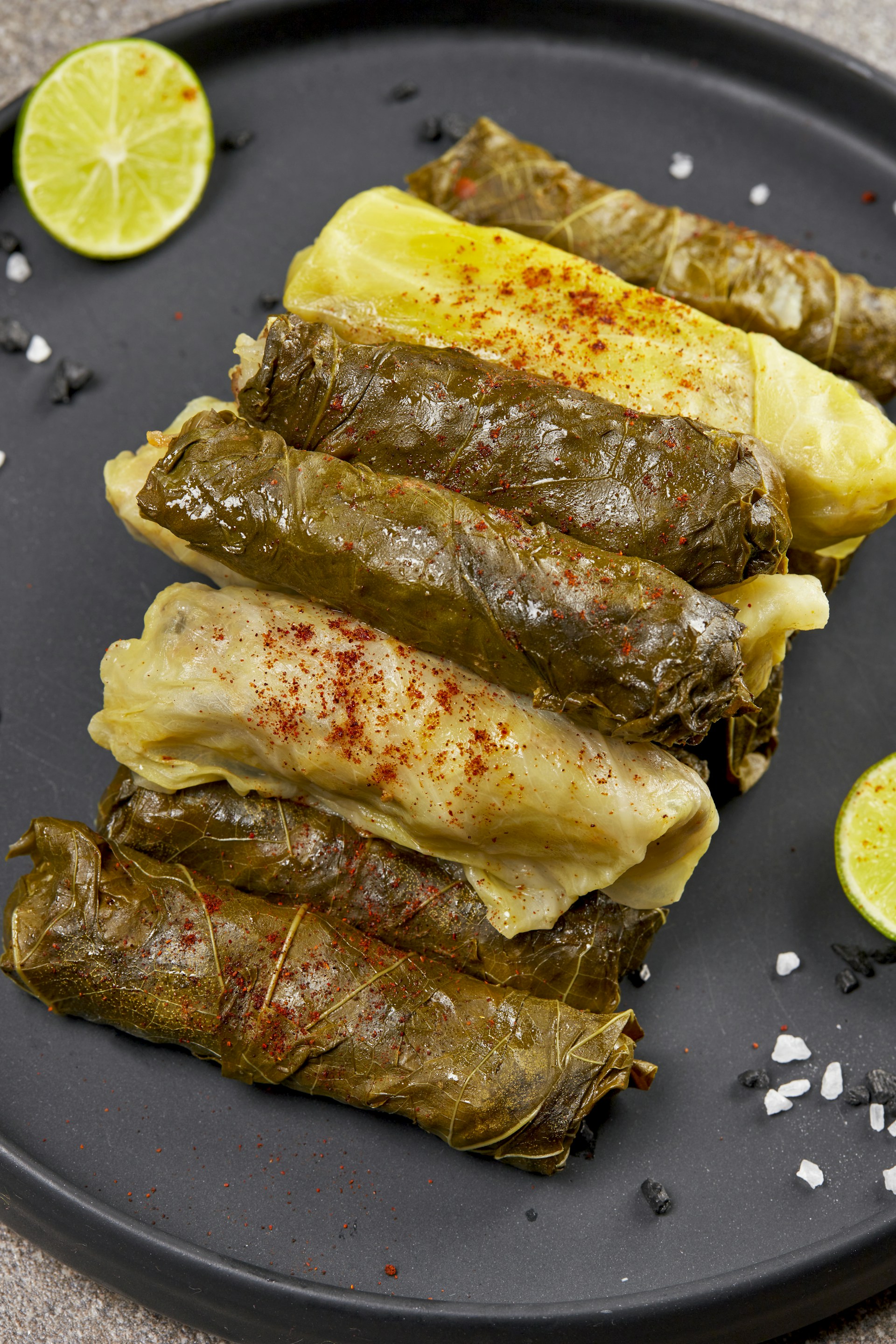 A close-up of a steaming plate of stuffed grape leaves, garnished with fresh herbs and lemon slices.