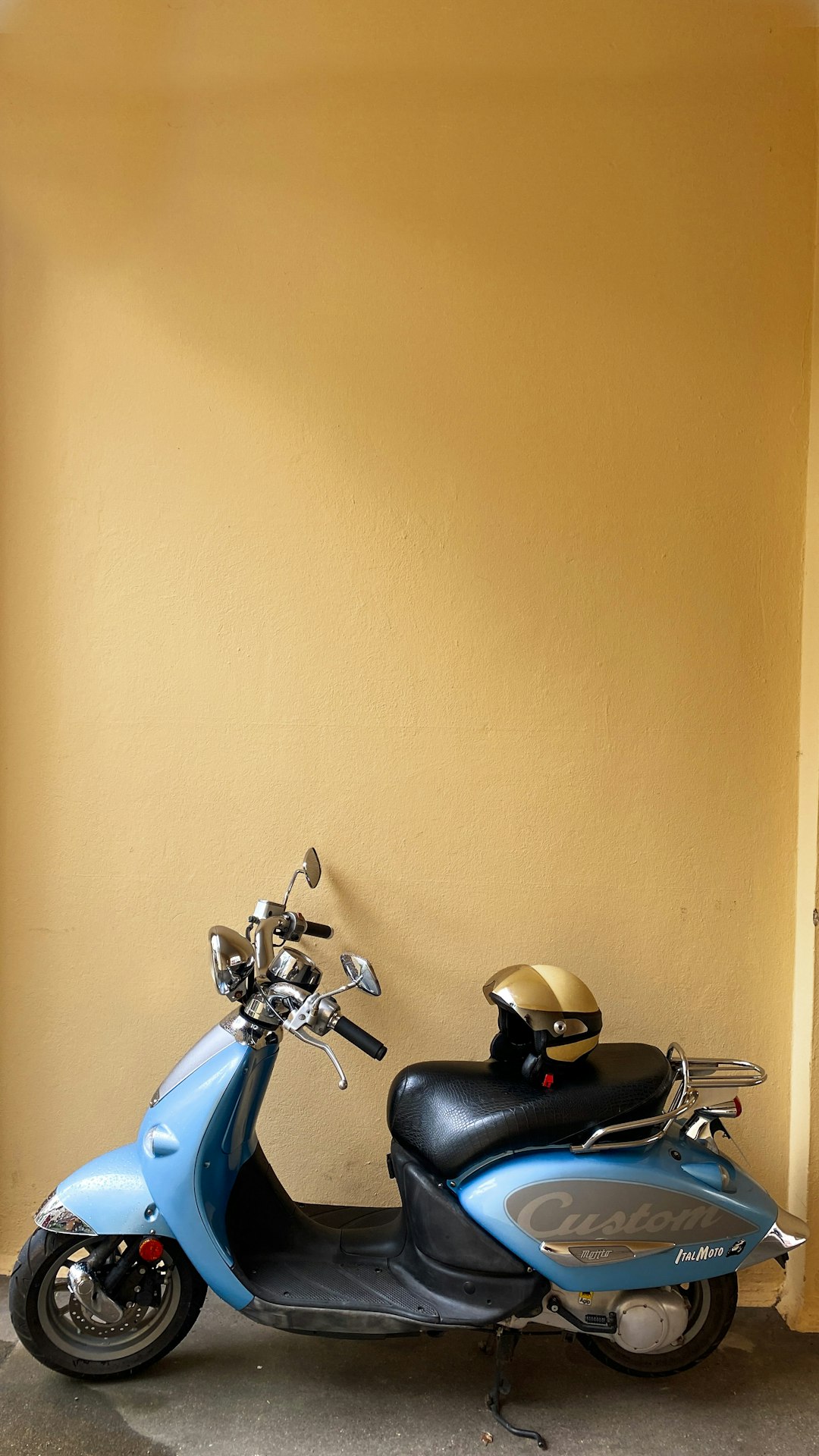 blue and black motorcycle parked beside beige wall