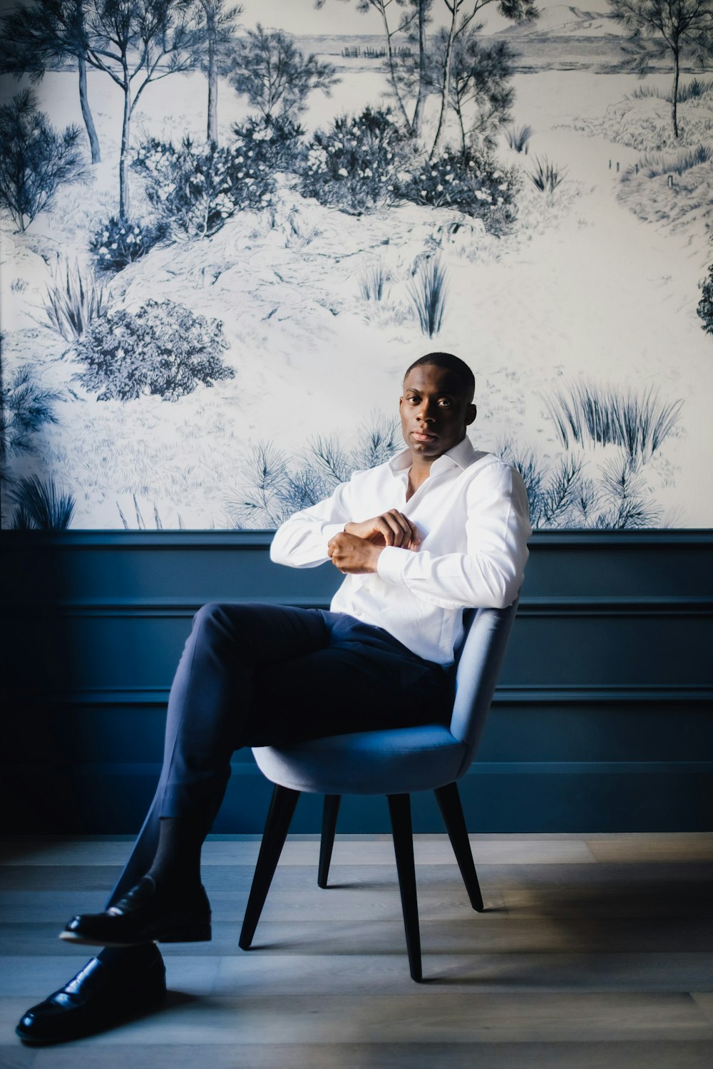 man in white dress shirt and blue denim jeans sitting on black wooden bench