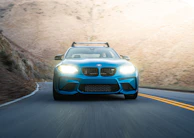 An overhead shot of a blue McLaren 720S cruising along a winding mountain road.