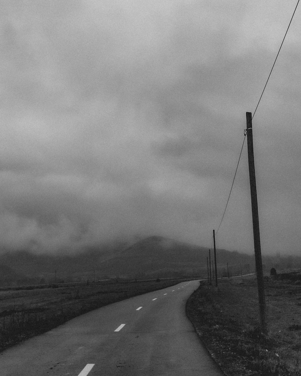 grayscale photo of road under cloudy sky