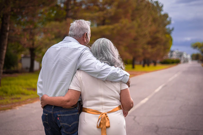 An elderly man outdoors with his caregiver, sharing a warm moment