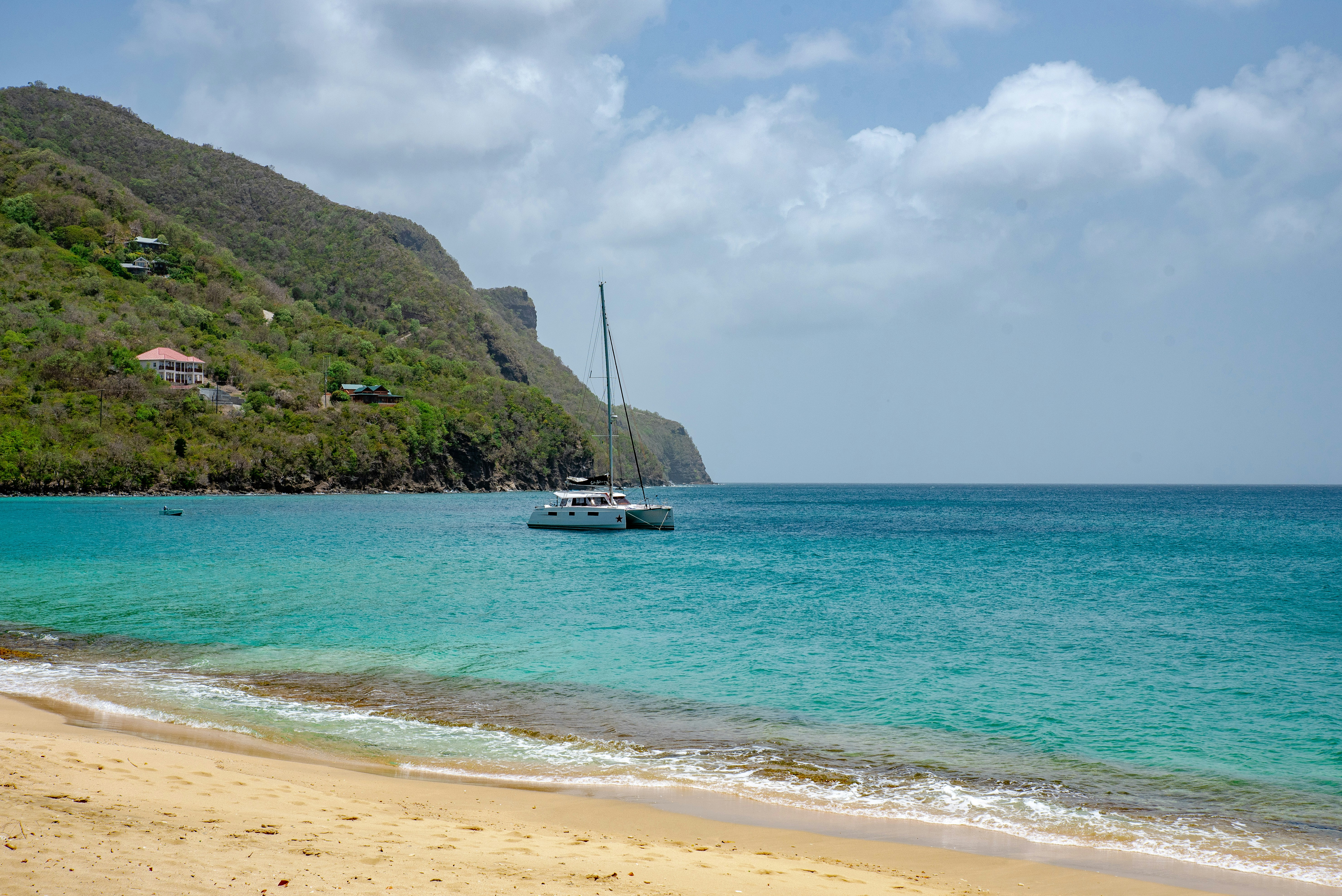 white boat on sea near green mountain under white clouds and blue sky during daytime, 