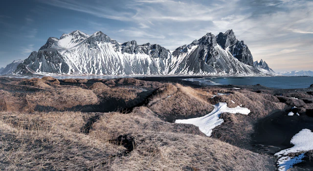 The jagged snow-capped peaks of Vestrahorn rising above black sand dunes at Stokksnes.