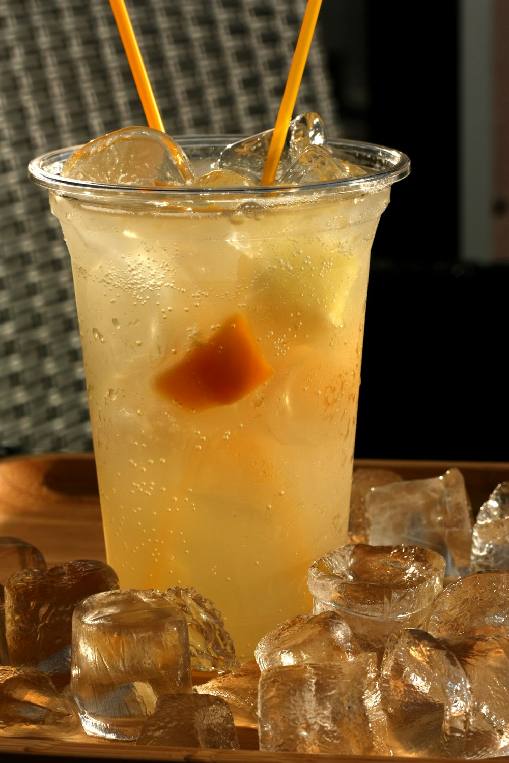 clear drinking glass with yellow liquid and ice cubes