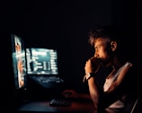 A person analyzing data on multiple monitors in a dark room.