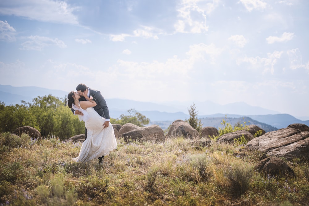 man and woman kissing on brown grass field during daytime