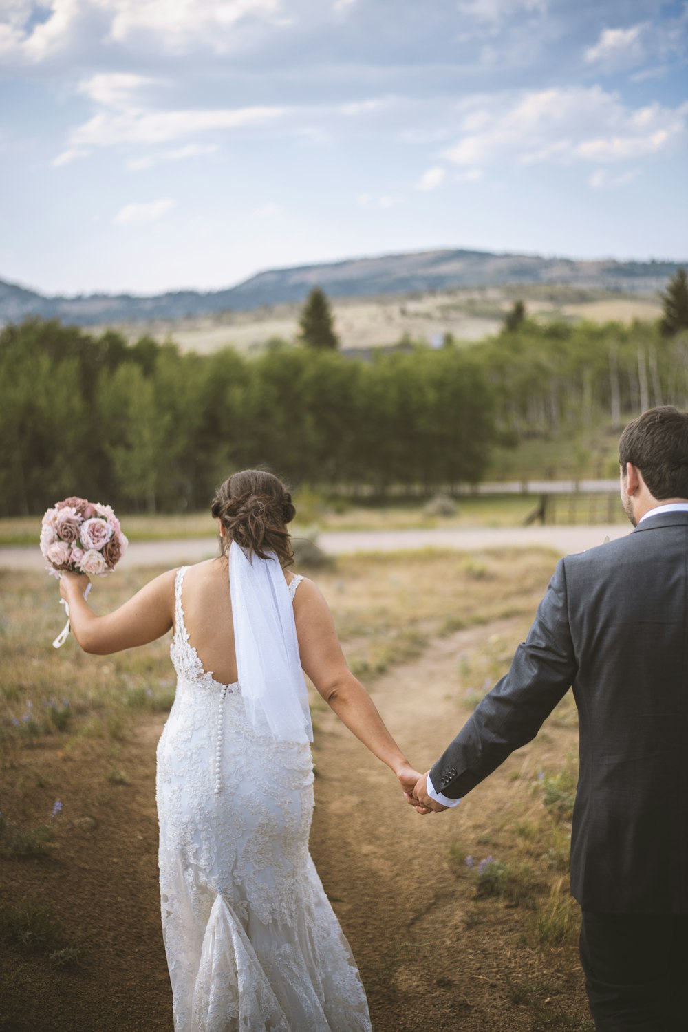 man in black suit holding woman in white wedding dress