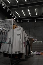 white polo shirt hanging on gray metal rack