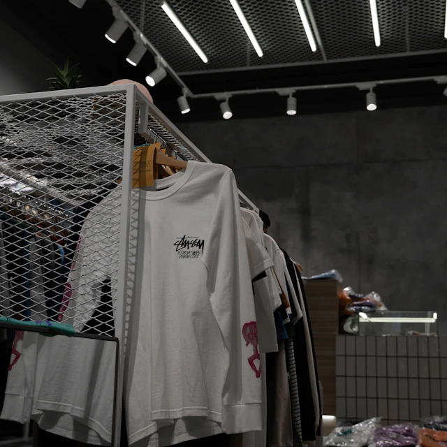 A white polo shirt hanging alone on a gray metal clothing rack