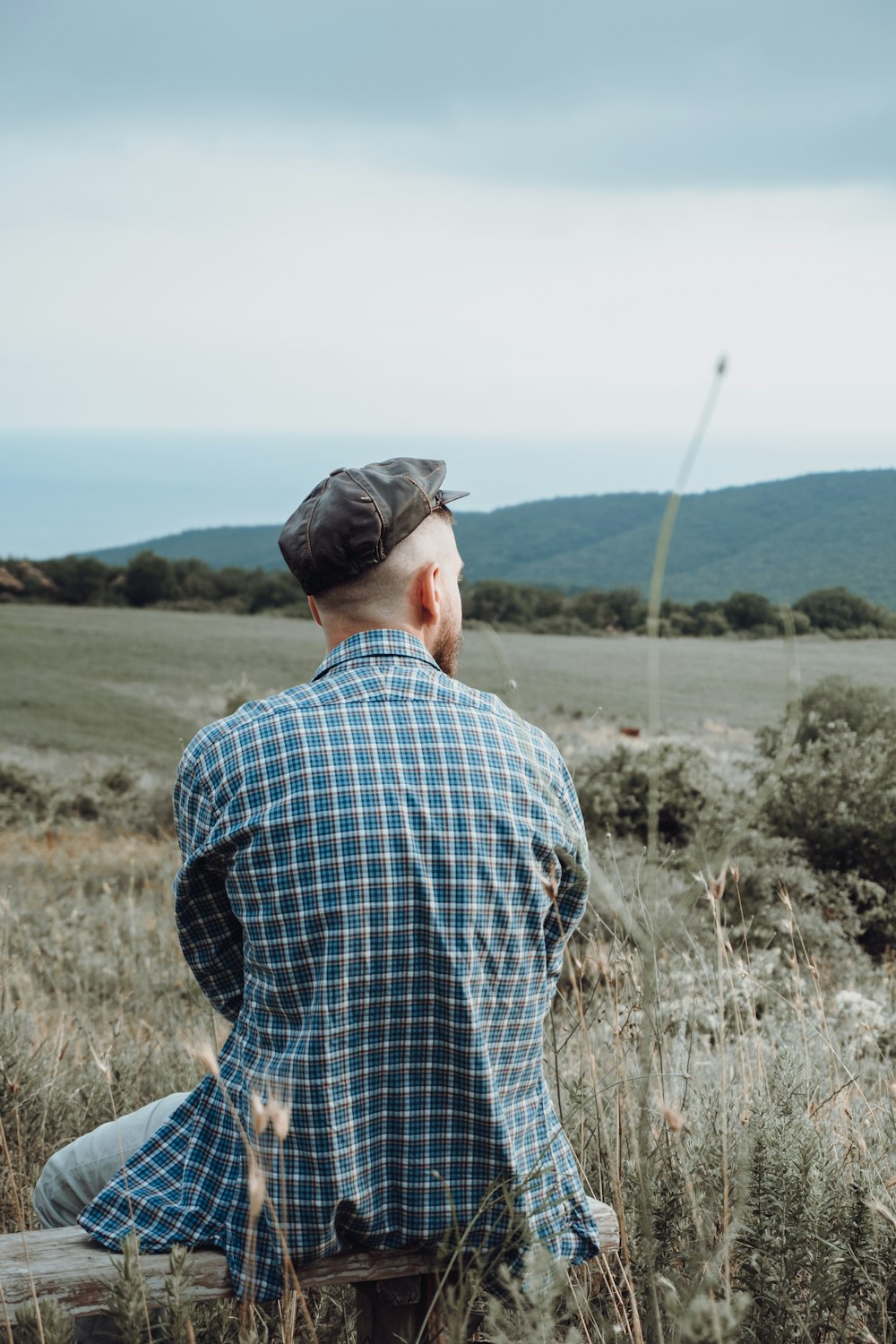 man in blue and white plaid dress shirt standing on grass field during daytime