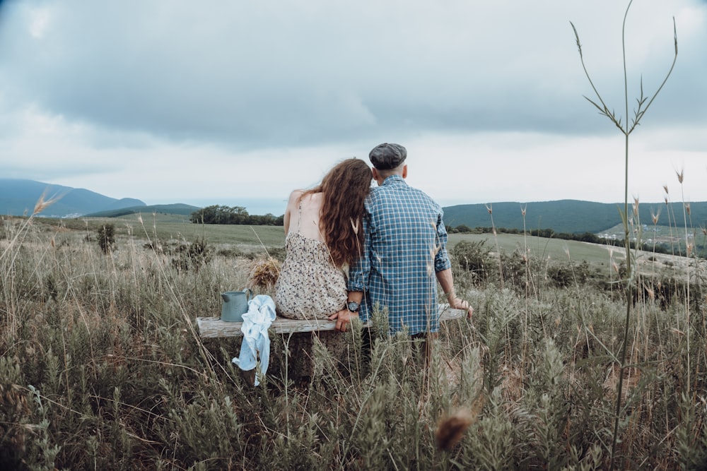 man and woman holding hands while walking on green grass field during daytime